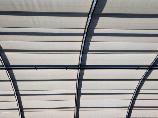 затенение застекленного потолка атриума здания. жалюзи под люком защищают интерьер от перегрева на солнце. автоматическая загрузка в сторону. окна на крыше в холле, галерея - Фото, изображение