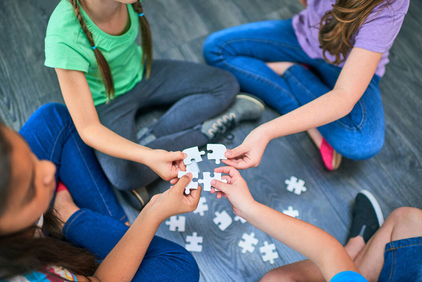 Learning is an important part of play. High angle shot of a group of kids holding a playing with puzzles together on the floor - Zdjęcie, obraz