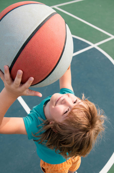 Close up portrait of a cute little child play basketball. Childhood and sport concept - Photo, image