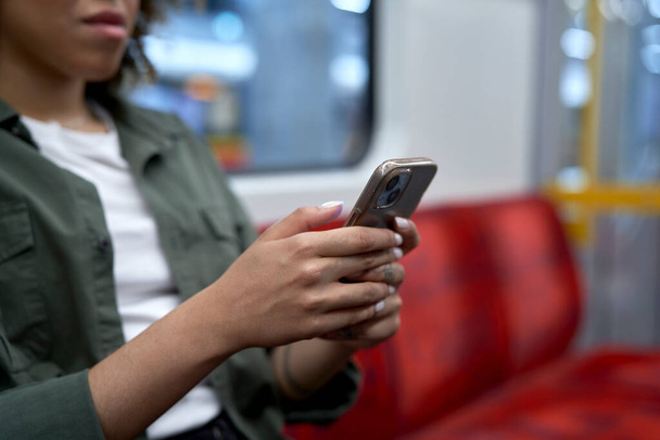Femme méconnaissable voyageant en métro et naviguant sur un téléphone mobile - Photo, image