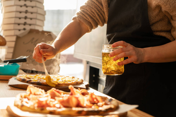 Close-up van een man en een vrouw handen bereiden pizza in de keuken in een restaurant, het leggen van het vlees en olie. op een zonnige dag, in het achtergrondlicht. Hoge kwaliteit foto - Foto, afbeelding