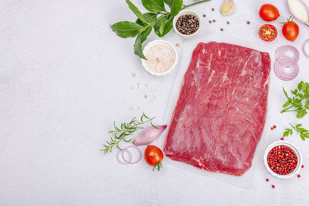 Dry aged Bavette Steak mit traditionellen Gewürzen und Kräutern. Frisches rohes Fleisch geschnitten, heller Steinbetonhintergrund, flache Lage, Draufsicht - Foto, Bild