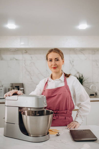Mladá žena používá mixér a šlehačku na dort, stojí v moderní kuchyni - Fotografie, Obrázek