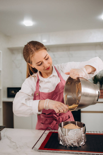 a woman is preparing cheesecake in the kitchen. - Фото, зображення