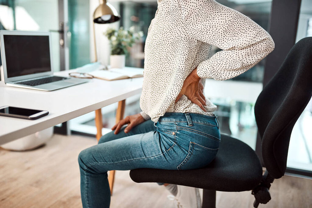 Feeling the tension flow straight to her back. Closeup shot of an unrecognisable businesswoman experiencing back pain while working in an office - Photo, Image
