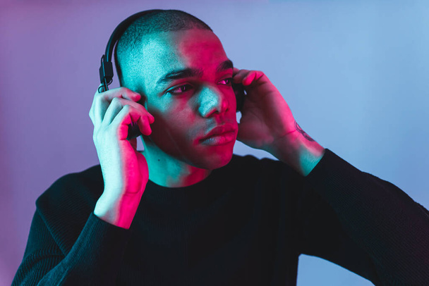 Afro-americký mladý muž se sluchátky poslech hudby a relaxační, modré pozadí. Kvalitní fotografie - Fotografie, Obrázek