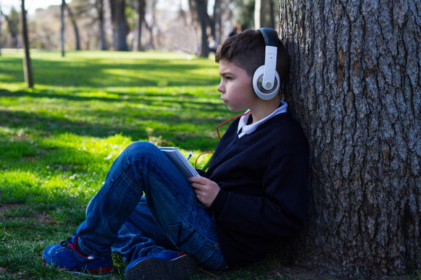Chlapec seděl na stromě se sluchátky - Fotografie, Obrázek