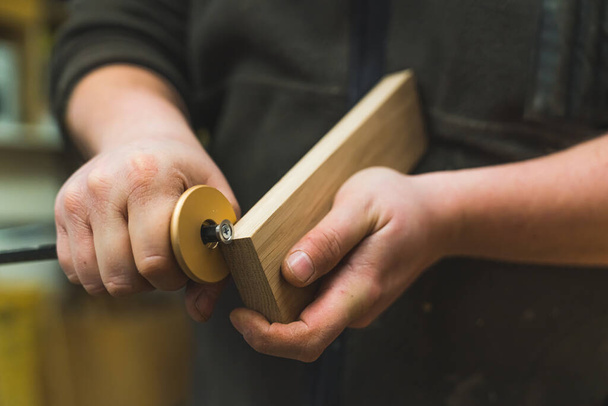 Mãos fechadas de um carpinteiro usando um calibre para marcar linhas em um bloco de madeira. Foto de alta qualidade - Foto, Imagem