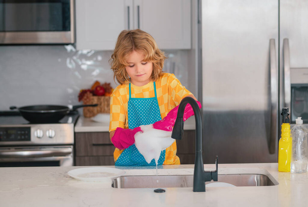 Cleaning house. Cute child helping with household, wiping dishes in kitchen. Adorable little helper child housekeeping. Little cute boy sweeping and cleaning dishes at kitchen - Fotó, kép