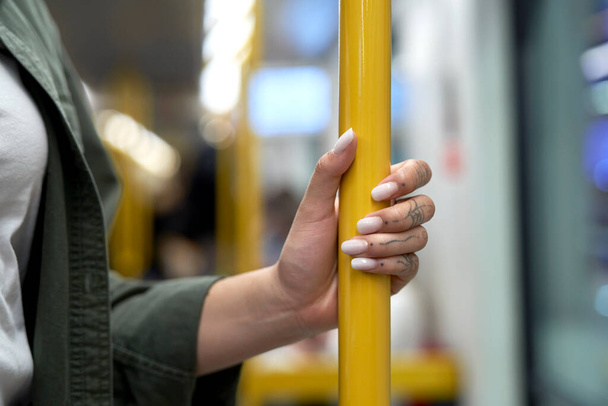 Hand of unrecognizable woman holding a handrail in the subway or train - Fotografie, Obrázek