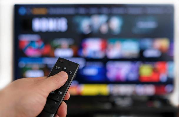 Binge watching a TV show - hand holding a remote control - Zdjęcie, obraz