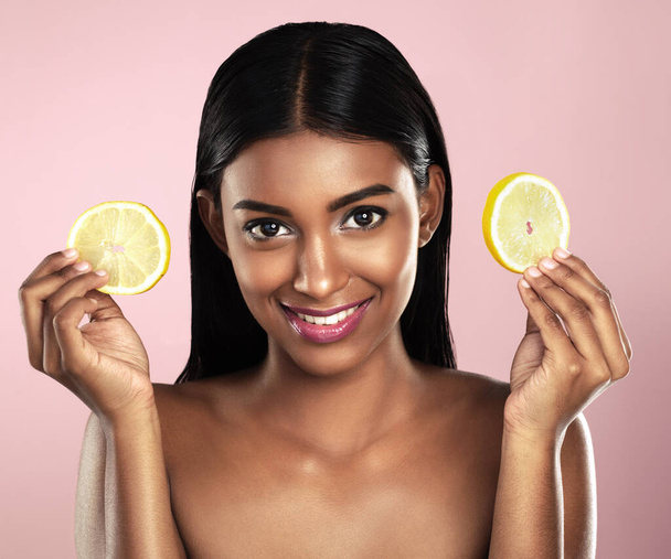 Face, skincare and happy woman with orange slices in studio isolated on a pink background. Fruit, natural cosmetics and portrait of Indian female model with food for detox, nutrition and vitamin c - Fotoğraf, Görsel