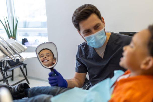 In dentistry. Dark-skinned boy talking to dentist before session - Zdjęcie, obraz