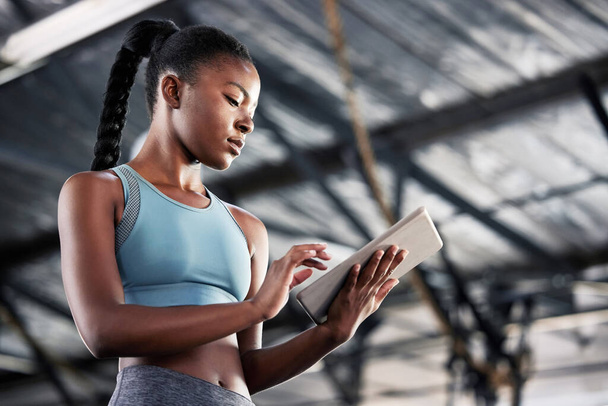 This app is like my personal trainer. a sporty young woman using a digital tablet at the gym - Fotoğraf, Görsel