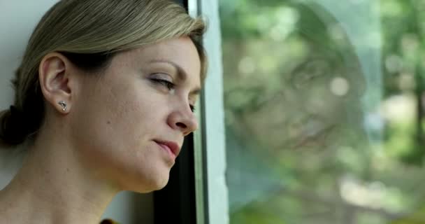 Θλιβερή γυναίκα βαριέται και κοιτάζει έξω από το παράθυρο 4k ταινία αργή κίνηση. Άγχος και κατάθλιψη από την έννοια μοναξιά - Πλάνα, βίντεο