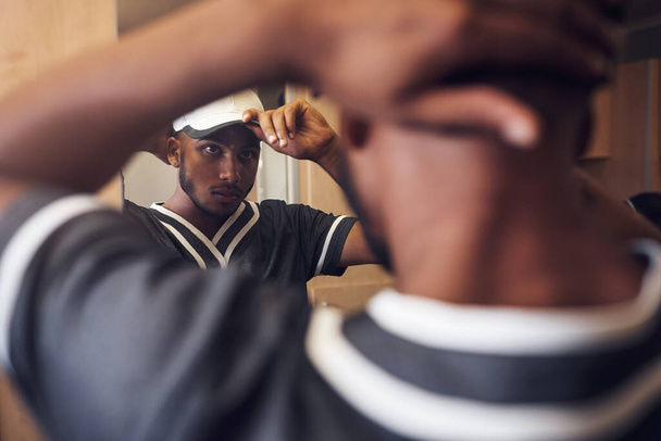 Baseball hráč, čepice a tvář sportovce v šatně se připravuje a oblékání v zrcadle. Za africkým sportovcem s reflexí a kloboukem pro sportovní soutěž, trénink nebo cvičení. - Fotografie, Obrázek