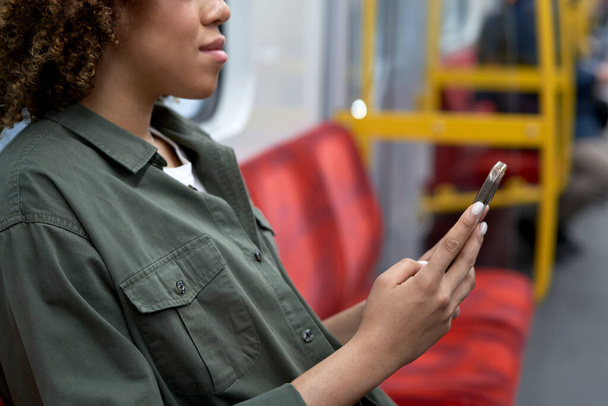 Αγνώριστη γυναίκα που ταξιδεύει με το μετρό και περιήγηση σε ένα κινητό τηλέφωνο - Φωτογραφία, εικόνα