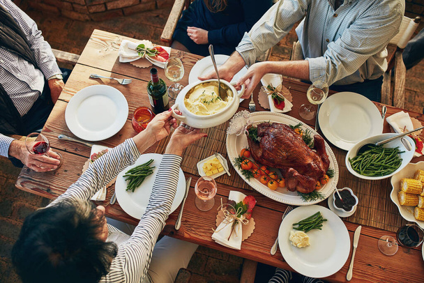 Comida, mesa e família comendo juntos para celebração de férias ou jantar com legumes saudáveis. Acima do grupo de pessoas ou amigos mãos compartilhando refeição almoço, frango ou peru com bebidas de vinho. - Foto, Imagem