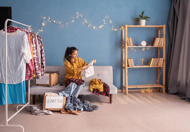 Femme tri et emballage des vêtements sur boîte de don dans sa chambre, concept de don. Espace de copie - Photo, image