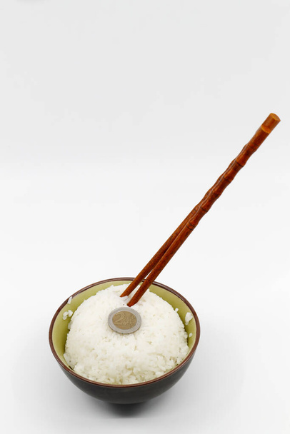 Χρήματα και φαγητό. Κέρμα σε μπολ με άσπρο ρύζι στον ατμό.   - Φωτογραφία, εικόνα