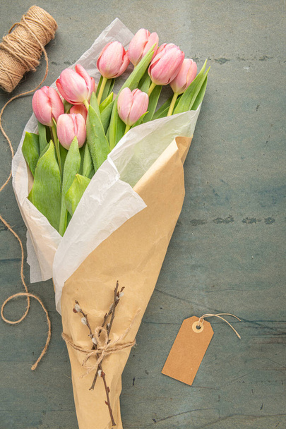 Pink tulip flowers bouquet on blue cement background. Flat lay, top view. Spring floral concept. - 写真・画像
