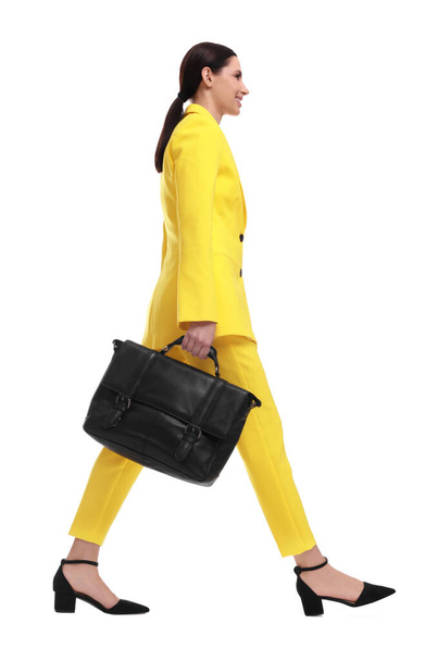 Beautiful businesswoman in yellow suit with briefcase walking on white background - Φωτογραφία, εικόνα