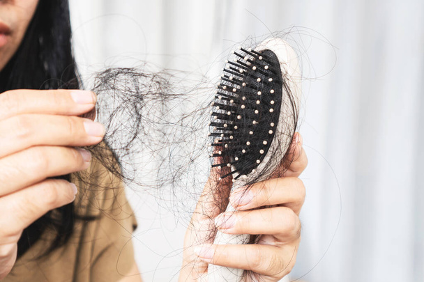 τριχόπτωση γυναίκες, closeup μαλλιά πέφτουν σε χτένα μετά το βούρτσισμα που προκαλείται από αλλεργία στο σαμπουάν, φάρμακο ή κατάθλιψη - Φωτογραφία, εικόνα