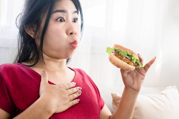 Aasialainen nainen onnettomuus suklaa ruokaa ja voi hengittää syödessään hampurilainen, joka juuttunut kurkkuun - Valokuva, kuva