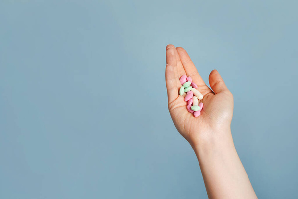 Mnohobarevné pilulky v ženské ruce na modrém pozadí, přičemž vaše léky - Fotografie, Obrázek