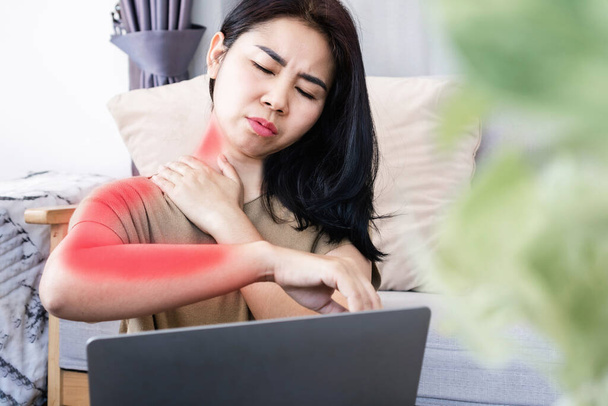 Asiatin leidet unter Nackenschmerzen, die sich auf Schulter und Unterarm ausbreiten, verursacht durch Überarbeitung eines Computers mit schlechter Körperhaltung - Foto, Bild