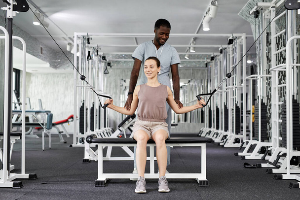 Retrato de la joven sonriente haciendo ejercicios de fisioterapia en el gimnasio en la clínica de rehabilitación - Foto, Imagen
