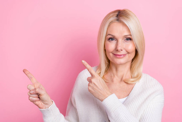 Portrait of satisfied funny person with blond hair wear white sweater indicating empty space proposition isolated on pink color background. - Foto, immagini