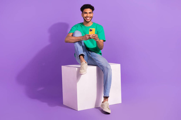 Full body cadre of young man platform box using smartphone gadget apple useful tips for comfort use isolated on purple color background. - Foto, imagen