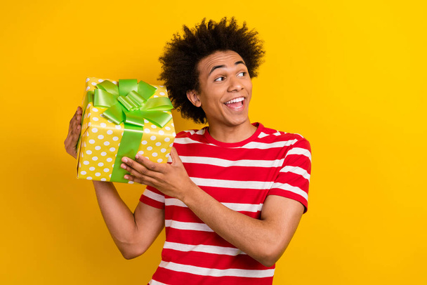 Portrait of astonished person arms hold giftbox look empty space isolated on yellow color background. - Foto, imagen
