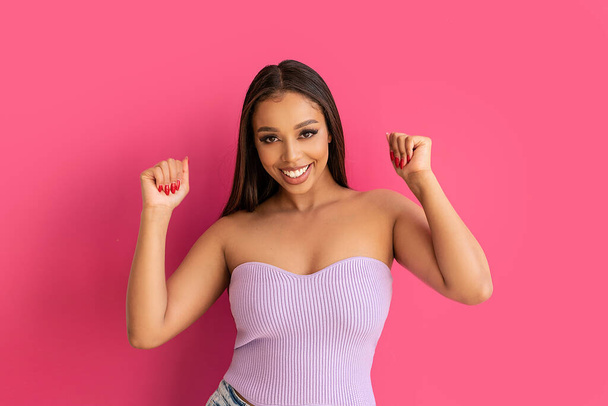 Joyful woman smiling, looking at the camera, posing on a pastel pink Studio Background. Real people emotions, toothy smile. Fashionable young girl, A lot of copy space. - Foto, imagen