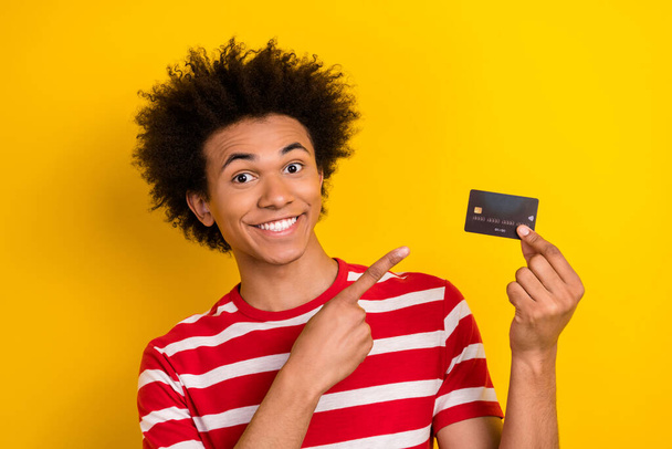 Photo of handsome guy indicate finger arm hold demonstrate debit card isolated on yellow color background. - Foto, imagen
