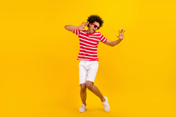 Full length photo of funky cool man wear striped t-shirt dark spectacles having fun dancing isolated yellow color background. - Foto, afbeelding