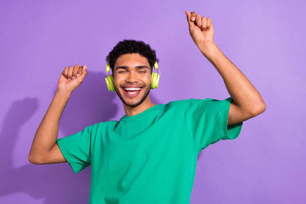 Photo of carefree funky man wear green t-shirt earphones dancing having fun isolated purple color background. - Фото, изображение