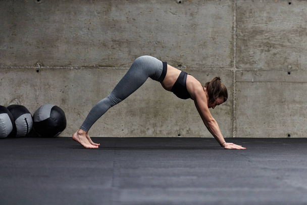 Modern bir spor salonunda formda bir kadın çeşitli egzersizlerle esneklik ve dayanıklılık göstererek spor yapmaya çalışıyor.. - Fotoğraf, Görsel