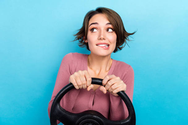 Photo of young girl guilty bite lips looking empty space hold steering wheel mistake on road accident isolated over blue color background. - Foto, imagen