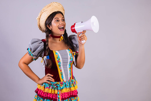 Brazilian woman, clothes from Festa Junina, Arraial, Festa de Sao Joao. Using megaphone, shouting and advertising, product, discount. - Фото, изображение