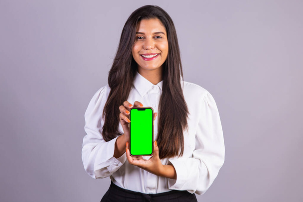 Brazilian woman holding smartphone, mobile. green screen. - Photo, image