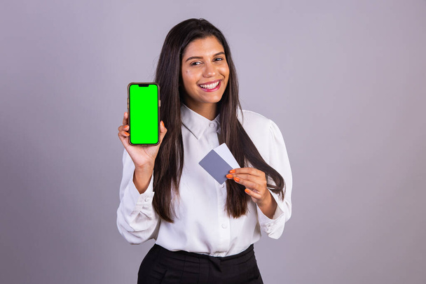 Brazilian woman holding smartphone, mobile. green screen. and credit cards. - Foto, afbeelding