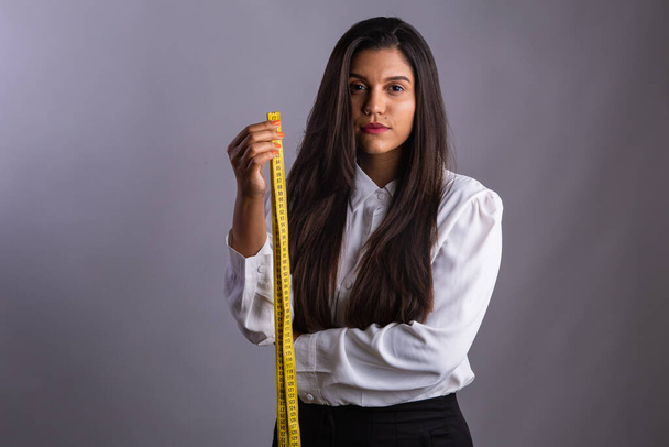 Brazilian woman, nutritionist, holding measuring tape. Horizontal photo. - 写真・画像
