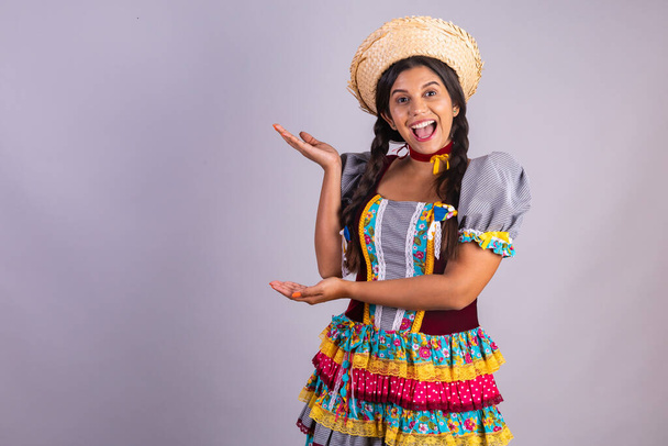 Brazilian woman, clothes from Festa Junina, Arraial, Festa de Sao Joao. presenting product or advertisement, publicity. pointing out. - Фото, зображення