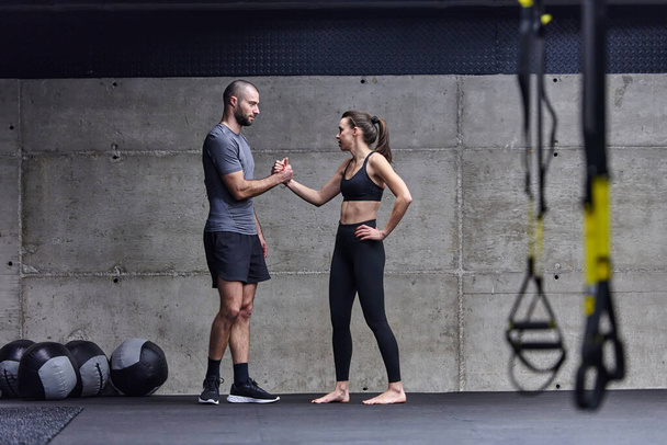 Muscular man and fit woman in a conversation before commencing their training session in a modern gym - Photo, Image