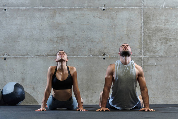 An attractive couple in the gym engaging in various stretching exercises together, showcasing their dedication to fitness, flexibility, and overall wellbeing. With synchronized movements, they - Foto, Bild