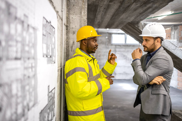 Работник строительства и инженер-строитель обсуждают новый этап проекта. - Фото, изображение