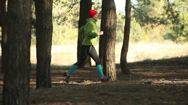Mujer corriendo en pista forestal en un día soleado, vistas laterales
 - Metraje, vídeo