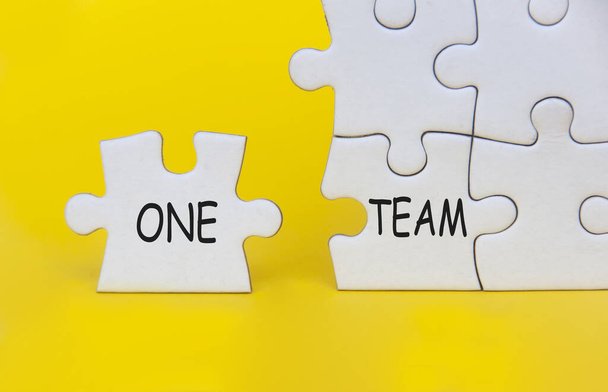 Ein Teamtext auf separatem Puzzle auf gelbem Hintergrund. Teamwork-Konzept. - Foto, Bild